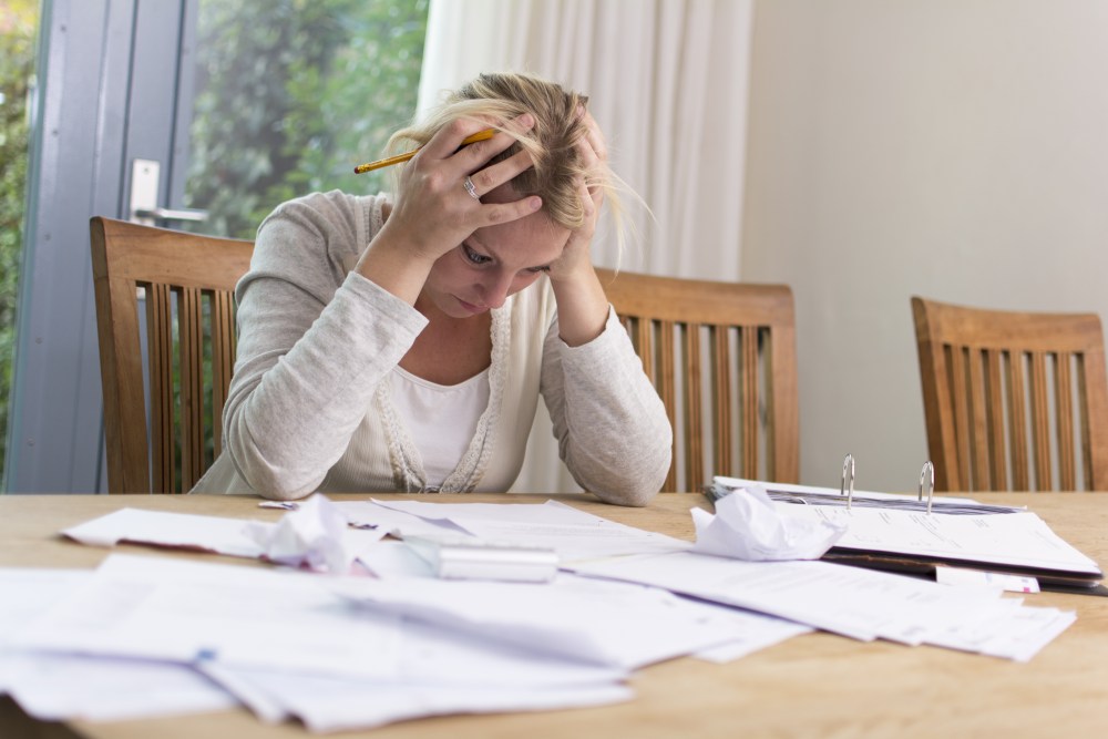 A stressed woman looking at a table full of medical bills