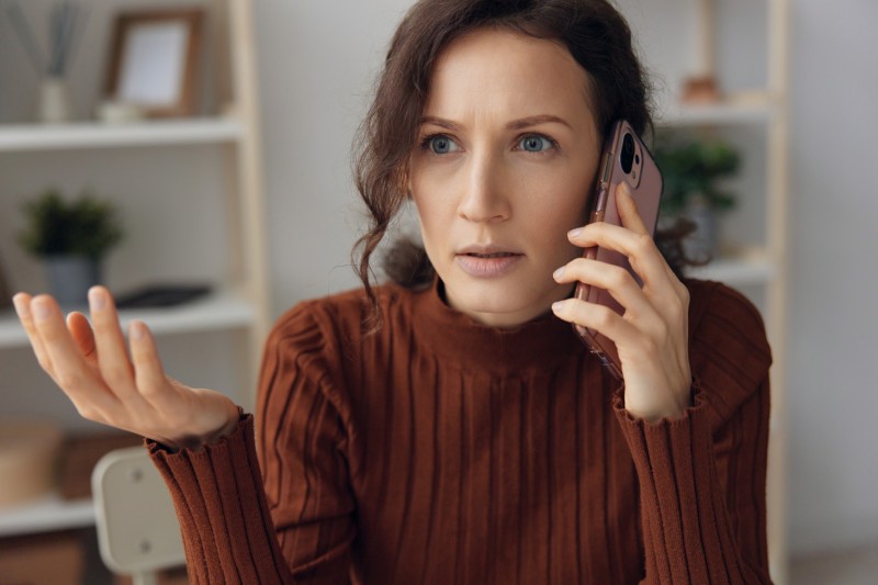 An unhappy woman on the phone with debt collectors