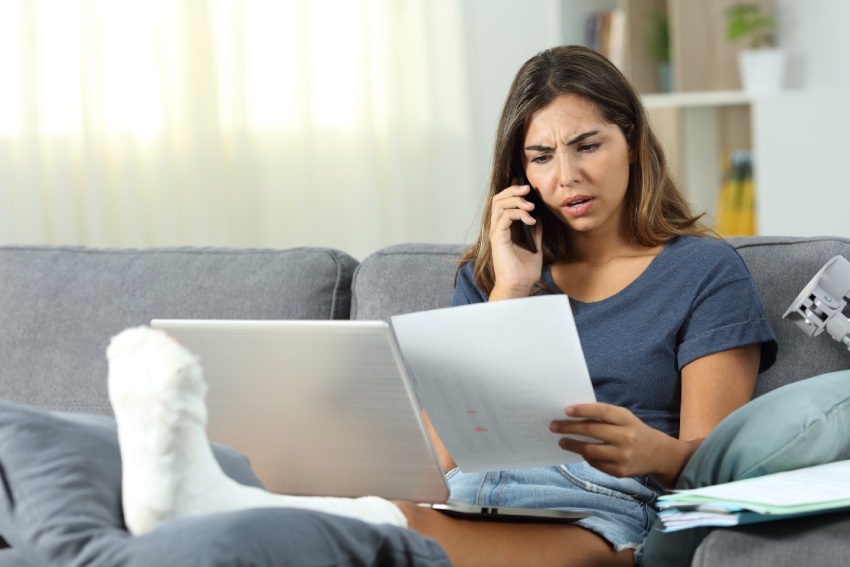 An upset woman with her foot in a cast on the phone