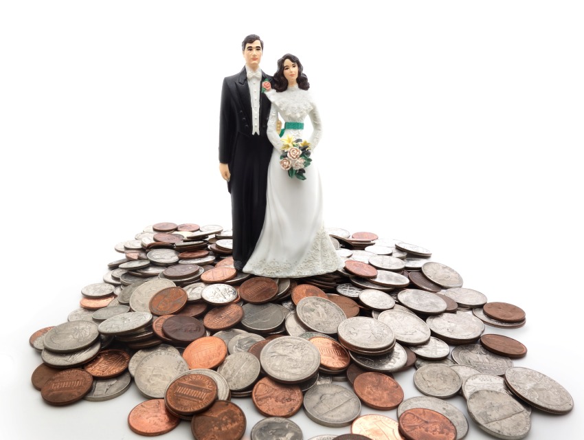 A wedding cake topper standing on a pile of money